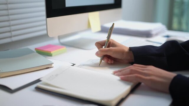 Close up of a female professional writing in a planner at her workplace. An organized person making a to do list for a new project