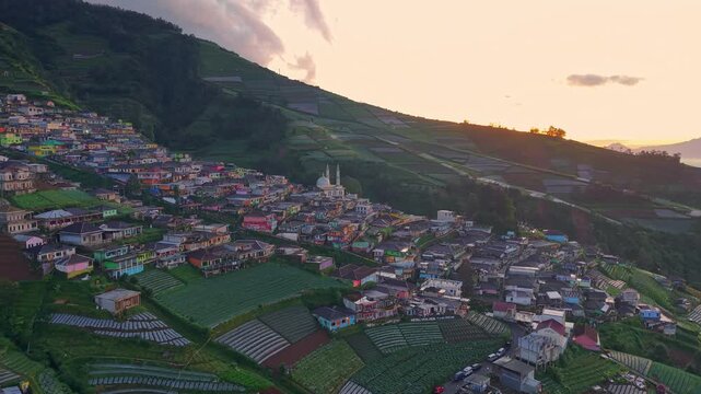 Scenic sunrise over rural village, terraced agriculture and glowing sky creating peaceful countryside panorama. Nepal Van Java, Indonesia.