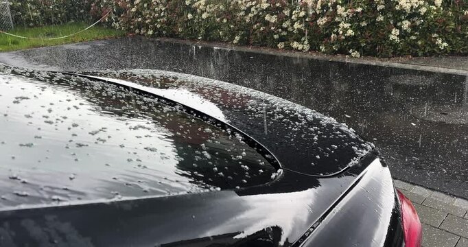 hailstones hitting a parked car during a hailstorm, suitable for weather damage, vehicle insurance, storm risk, natural hazards, and automotive protection concepts.