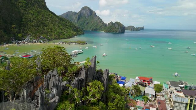 Aerial flypass of Taraw Cliff canopy walk revealing Bacuit Bay with fishing boats and El Nido town port Palawan Philippines