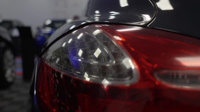Close up of illuminated rear taillight on red luxury sports car, flashing red orange twice