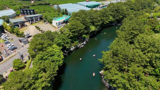 High-angle aerial view of emerald valley river and pine forest in Soesokkak, Jeju Island, South Korea
