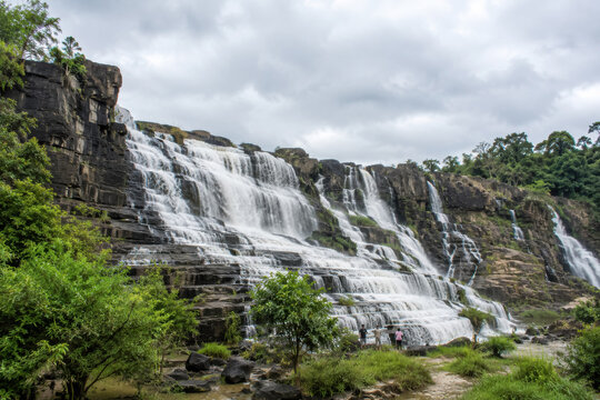 Wide stepped waterfall flowing over dark rocks in lush Da Lat valley.generative AI
