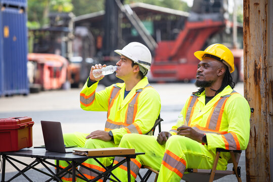 Industrial workers taking a break at shipping container terminal, Diverse logistics team drinking water and resting at port facility, Professional maintenance crew relaxing during shift at cargo yard
