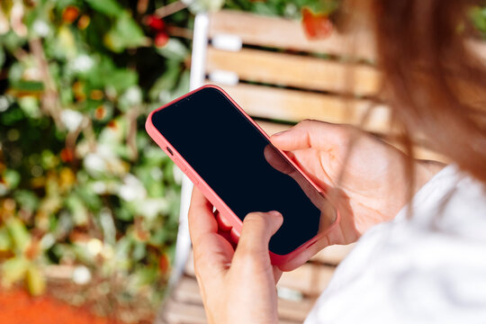 Close-up of a person holding a smartphone outdoors.