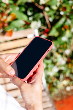 Close-up of a person holding a smartphone outdoors.