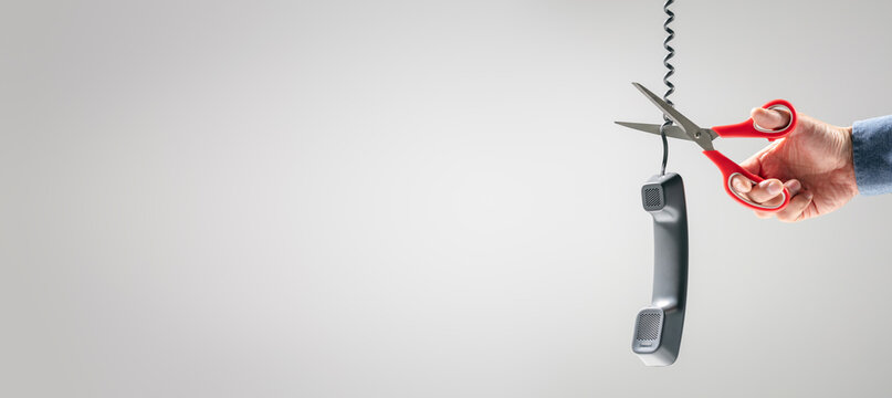 Scissors cutting telephone line connection to end call or terminate phone contract background
