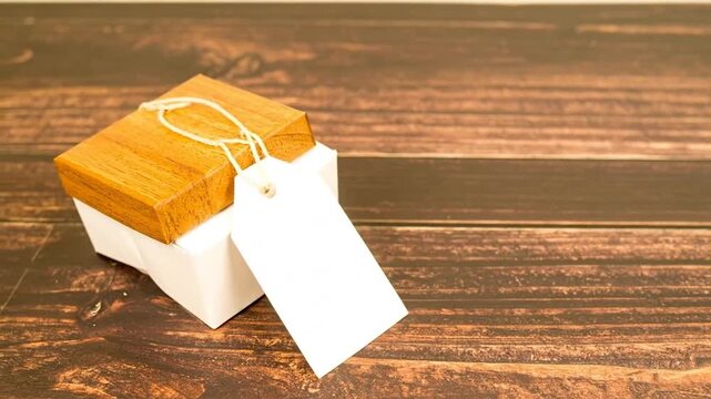 A small wooden gift box with a blank tag on a wooden surface