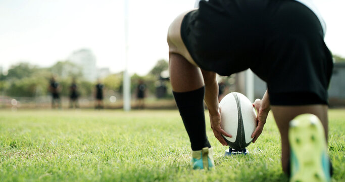 Rugby ball, hands and player on field with kick, start game or match for competition or challenge. Sport, person and football on tee for tournament, score or accuracy practice with fitness and space