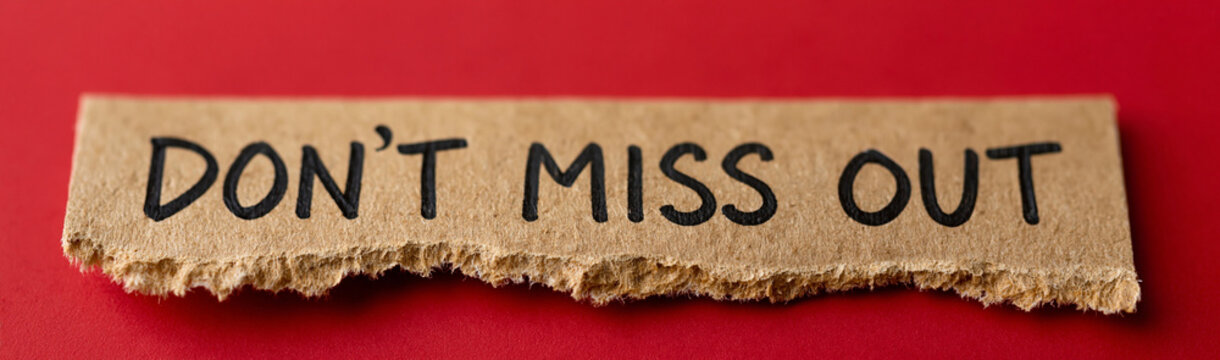 Don't Miss Out Note: A torn piece of brown cardboard with DON'T MISS OUT scrawled in black marker sits on a vibrant red background, urging viewers to seize an opportunity.