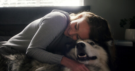 Cuddle, husky and love with woman in home living room for affection, bonding or security. Animal care, hugging and smile of happy dog owner on sofa in apartment for companionship, loyalty or trust © peopleimages.com