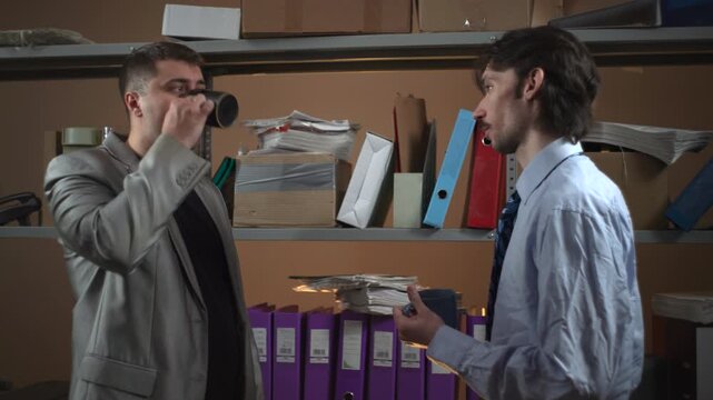 Two men talking in an office storage room