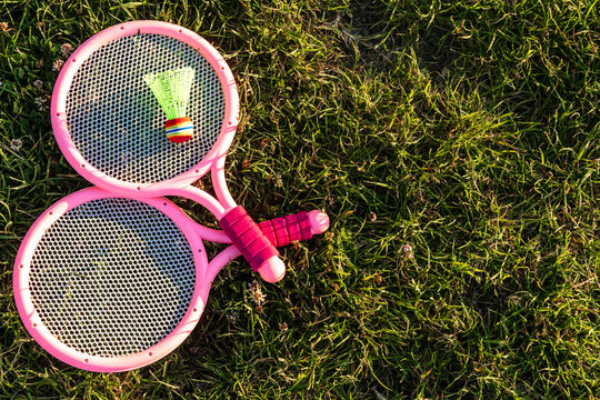 Pink badminton rackets and a shuttlecock on green grass.