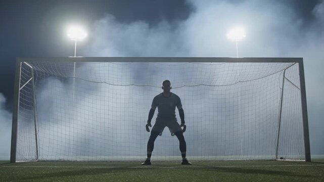 Goalkeeper silhouette waiting beside the goal in a night arena with suspenseful match mood for sports teaser trailers and broadcast campaigns