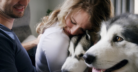 Hug, husky and love with couple in home living room for affection, bonding or security. Animal, cuddle and smile of happy dog owner people in apartment together for care, companionship or loyalty © peopleimages.com