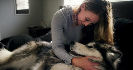 Cuddle, dog and love with woman in home living room for affection, bonding or security. Animal care, hugging and smile of happy husky owner on sofa in apartment for companionship, loyalty or trust © peopleimages.com