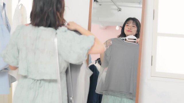 アパレルショップで鏡を見ながら洋服を選ぶ女性