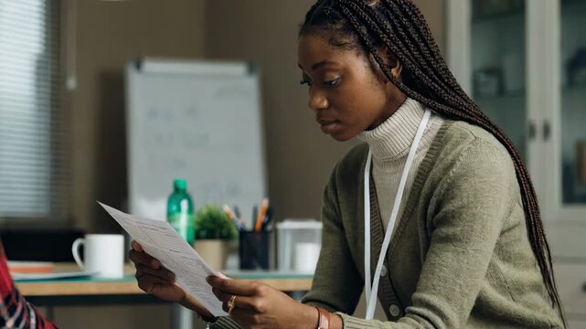 Medium shot of a nurse reviewing a patients health questionnaire with a focused expression in a softly blurred clinical office environment.