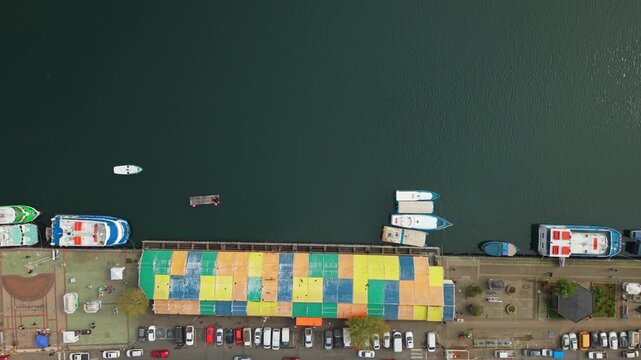 Top down aerial view of the Valdivia River Fair in Chile near Schuster Pier, with tourist boats cruising along the Calle Calle River