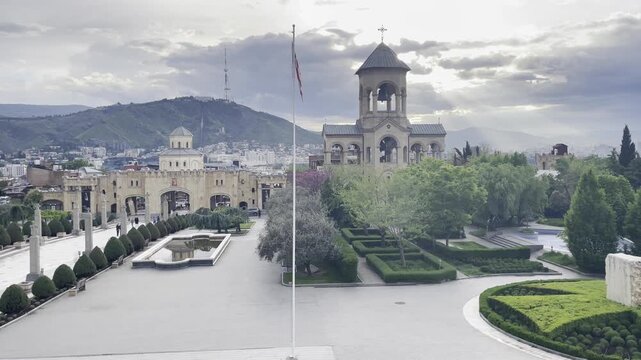 High angle view of Holy Trinity Cathedral complex courtyard in Tbilisi with traditional stone bell tower and gardens. Famous religious architecture landmark and travel destination in Georgia.