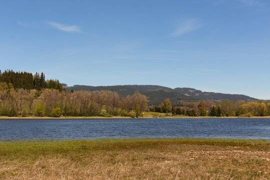 A serene lakeside scene with clear blue water reflecting the sky - Lake Lipno in Czech Republic