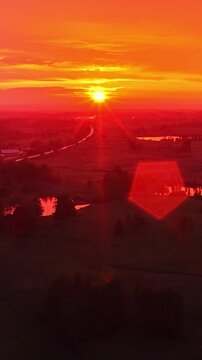 Aerial view of a vivid orange sunset over a winding river and rural landscape