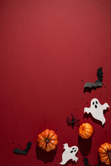 Obraz premium Autumn Halloween arrangement with pumpkin ghost bat and spider on vertical red textured background
