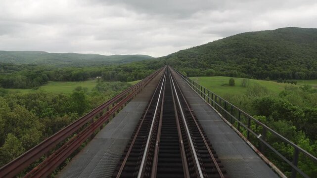 view from back of new jersey train from moodna viaduct of valley between mountains upstate new york (transit rail track railroad travel commute commuter line) port jervis new york