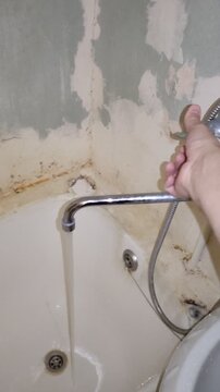 Water running from faucet into old peeling bathtub, vintage film effect with grain and dust