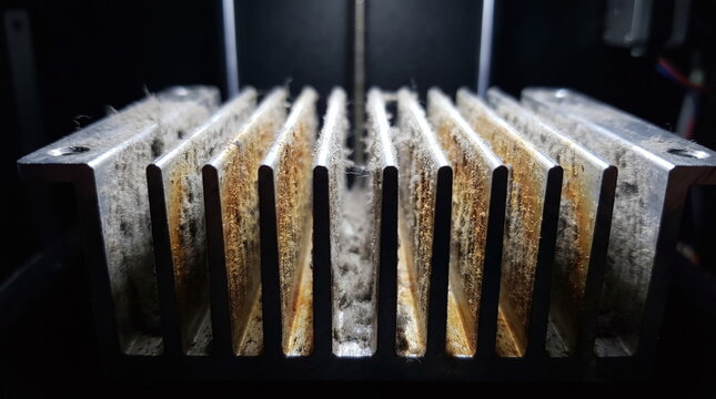 Macro close up of a dirty aluminum heat sink covered in thick dust and grime inside a 3d printer