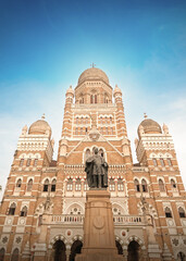 Obraz premium Mumbai Maharashtra India Jan 18 2026 Wide angle low angle view of the bronze statue of Sir Pherozeshah Mehta standing before the majestic Gothic Brihanmumbai Municipal Corporation building