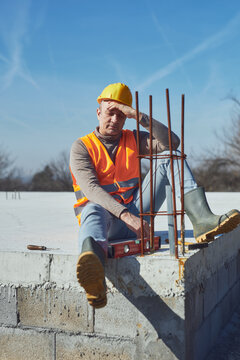 Construction worker having a heatstroke on a hot sunny day, headache, issues on a construction site outdoors.