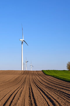 Wind turbines at sunset in green field &ndash; renewable energy, clean power, sustainable future.