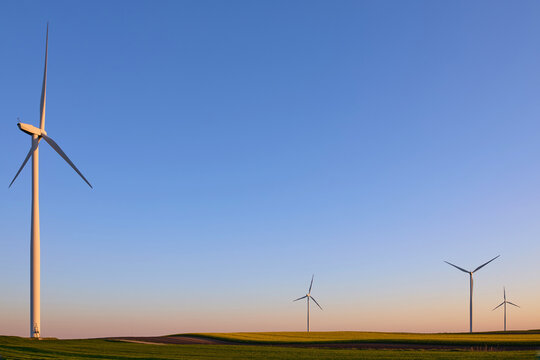 Wind turbines at sunset in green field &ndash; renewable energy, clean power, sustainable future.