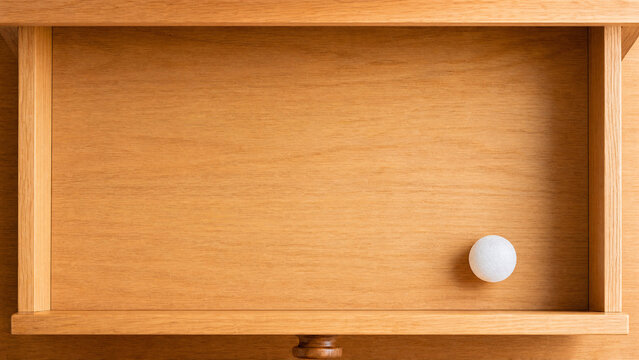 Single camphor ball in wooden drawer, household freshness and protection concept.