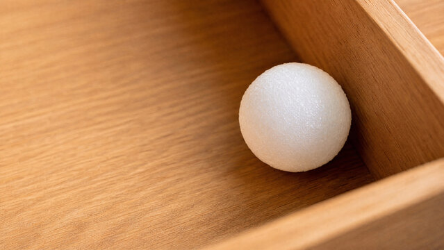 Single camphor ball in wooden drawer, household freshness and protection concept.