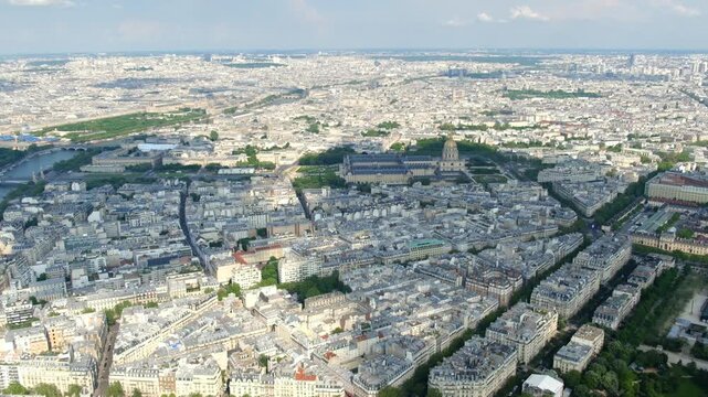 Expansive aerial view of paris cityscape revealing les invalides and the seine river on a sunny day with clouds casting shadows over the historic european architecture