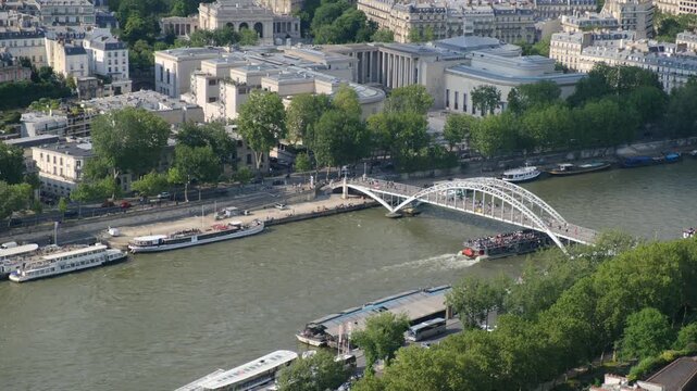 Aerial view of the river seine in paris with tourist boat passing under the passerelle debilly footbridge, showcasing the stunning parisian architecture and city life