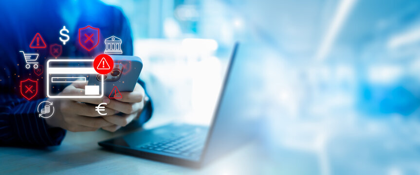 Online payment fraud detection and cybersecurity threat alert concept. Man using smartphone and laptop with credit card, warning icon, and digital security interface for mobile banking safety