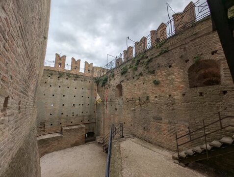 Imponente castello in pietra con torri merlate e mura storiche sotto un cielo grigio, per un&rsquo;atmosfera medievale forte e suggestiva