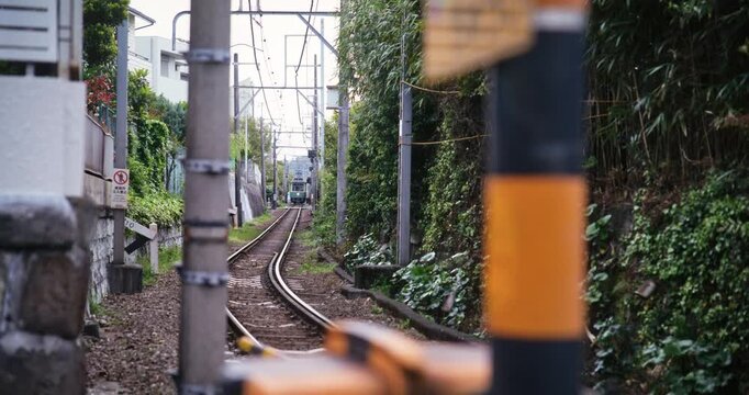 Slow motion shot of train tracks and distant train in Japanese town