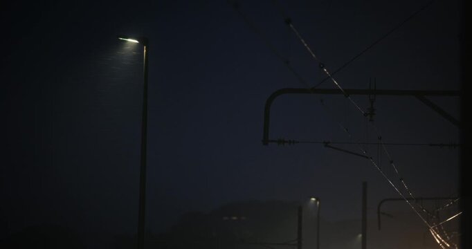 Heavy wind and rain near light post and tram wires at night