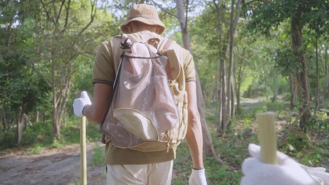 Boy Placing Litter into Reusable Mesh Bag During Forest Trail Cleanup