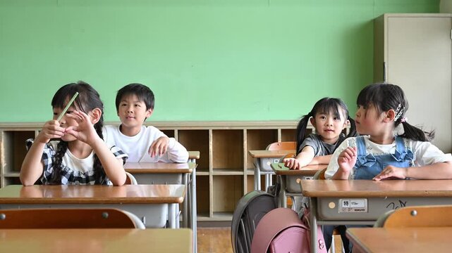 教室の席に座って授業を受ける自然な表情の女子小学生たち	