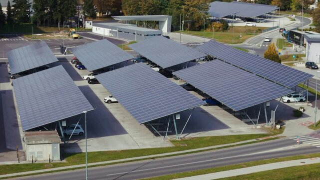 Aerial view shows a parking lot with solar canopies covering vehicles and generating energy in an urban area.