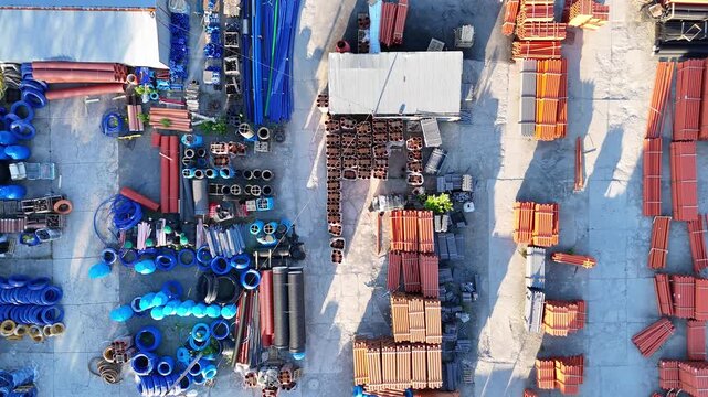 Aerial view of an industrial pipe warehouse showcasing a variety of colorful pipes, stacks of materials, and organized storage areas in a well-maintained outdoor setting