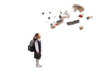 Obraz premium Surprised schoolgirl standing and looking at flying books