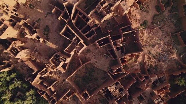 Abandoned mudbrick ksar in Tinghir, Draa-Tafilalet, southeastern Morocco, showing dense earthen architecture, fortified compounds and desert oasis urban layout, slow top down ascent shot.