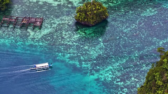 Spectacular wide drone shot over Sohoton Cove in the Philippines. Features boats cruising through crystal-clear turquoise lagoons surrounded by lush, green limestone karst islands and morning mist.