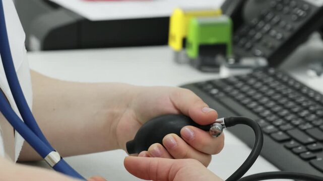 Nurse hand pumps blood pressure monitor examining patient in clinic closeup. Female doctor tests woman cardiovascular system in hospital slow motion